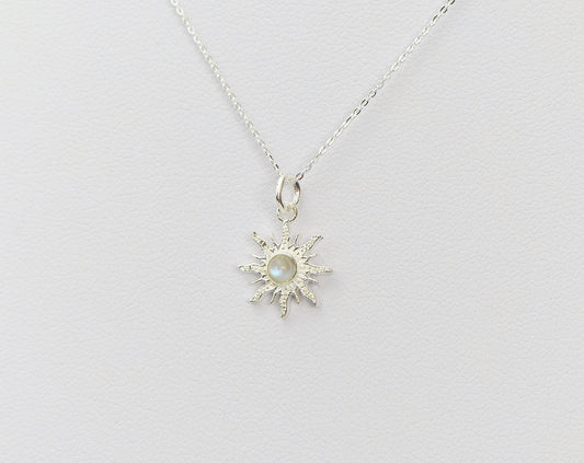 Dainty celestial pendant necklace with a moonstone centre and sun-ray design in silver, shown against a white surface.
